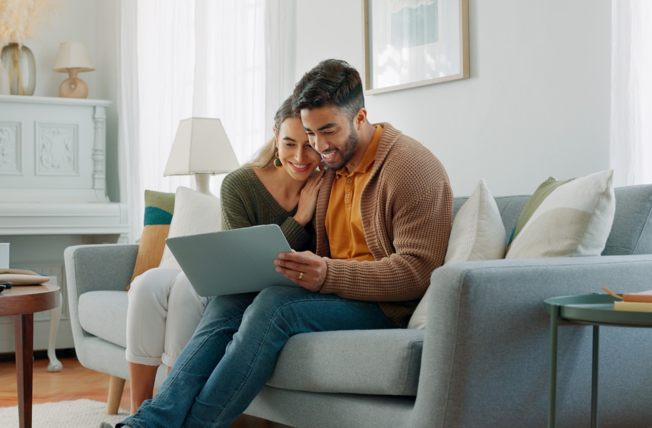 Young people on couch with pc internet, planning future together